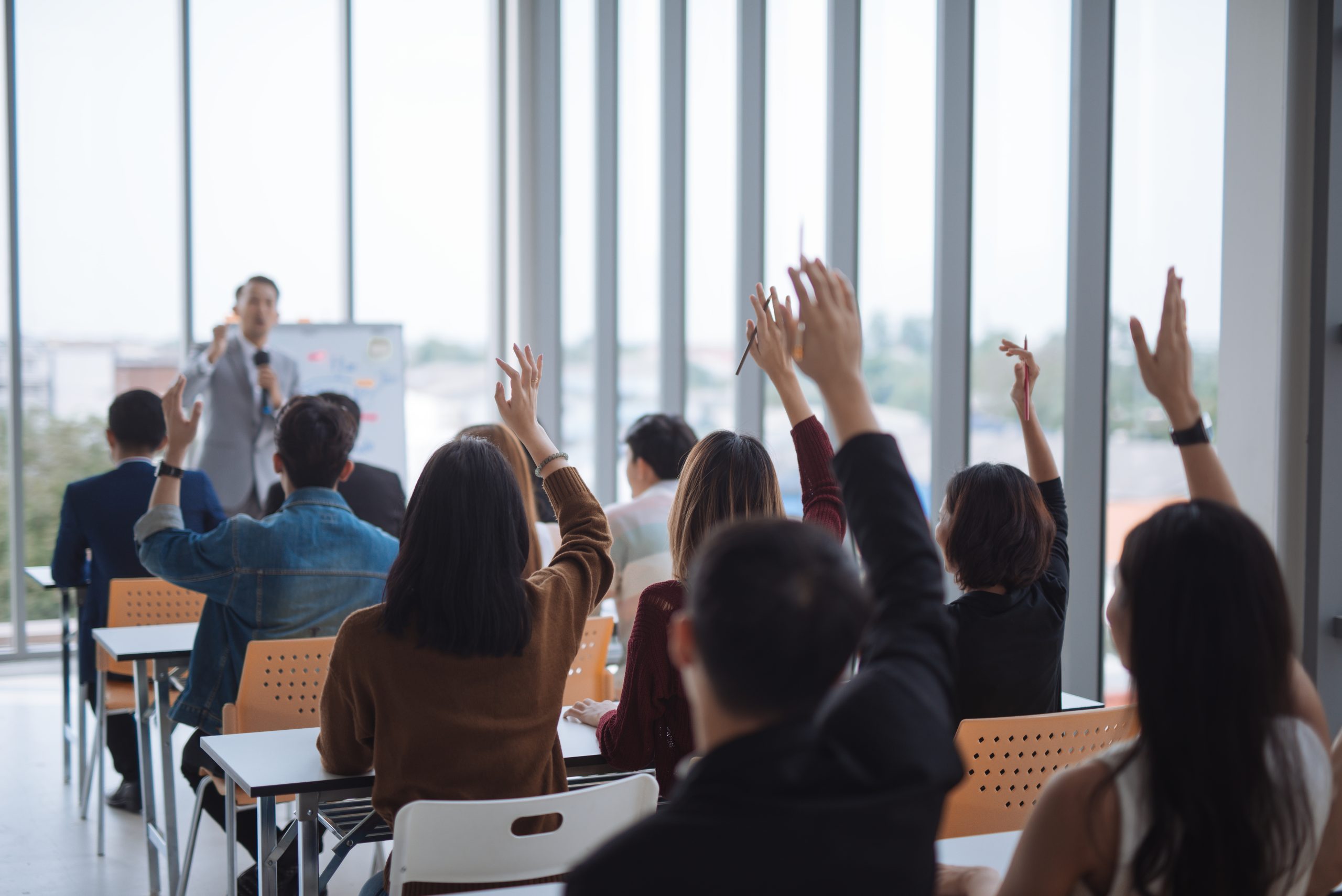 raised-up-hands-arms-large-group-seminar-class-room-agree-with-speaker-conference-seminar-meeting-room